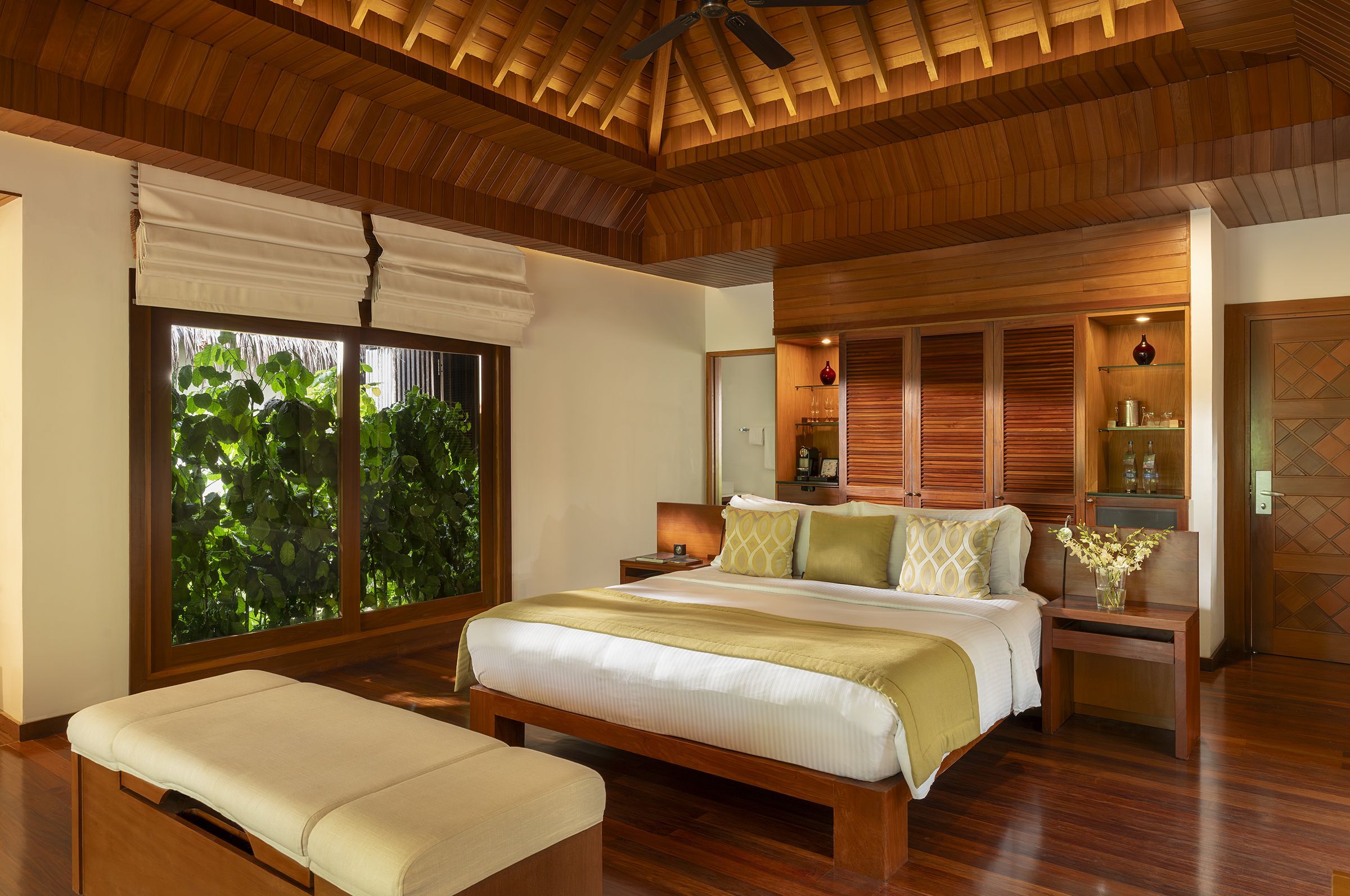Bedroom of a Baros Villa with its wooden terrace and garden outside