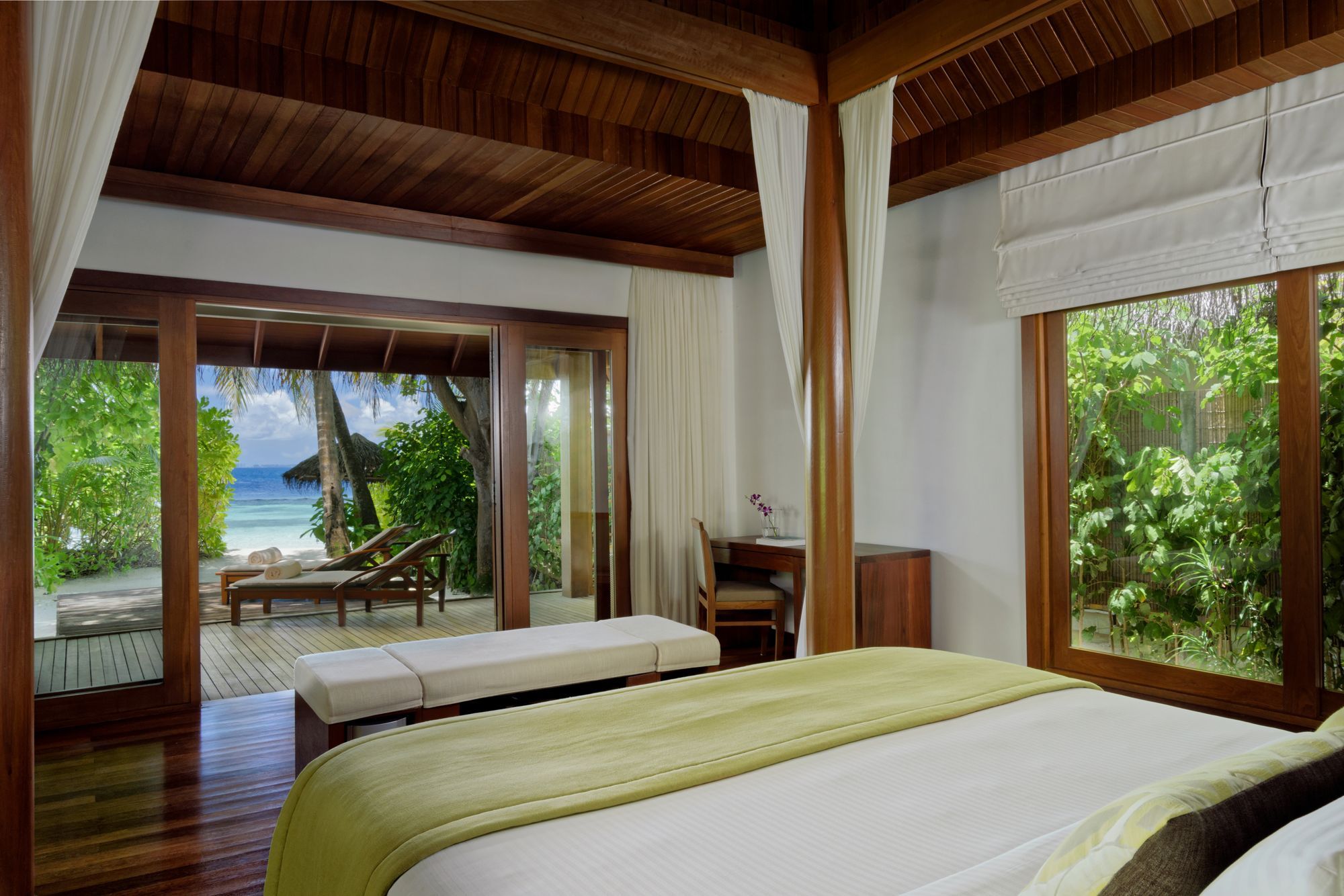 Four-poster bed in a Baros Villa, with a view through to the beach