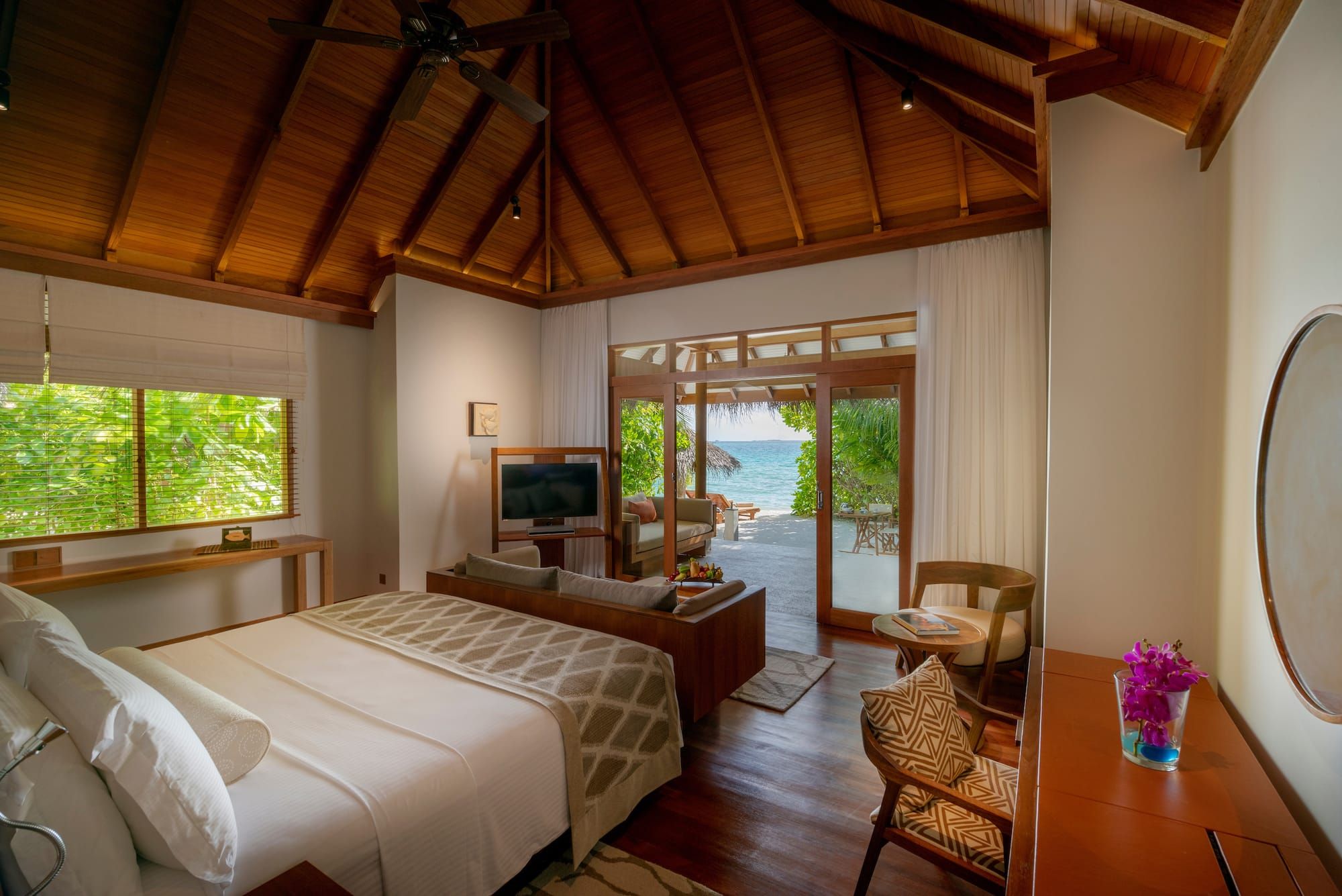 Villa bedroom with timber vaulted ceiling and doors open to the beach