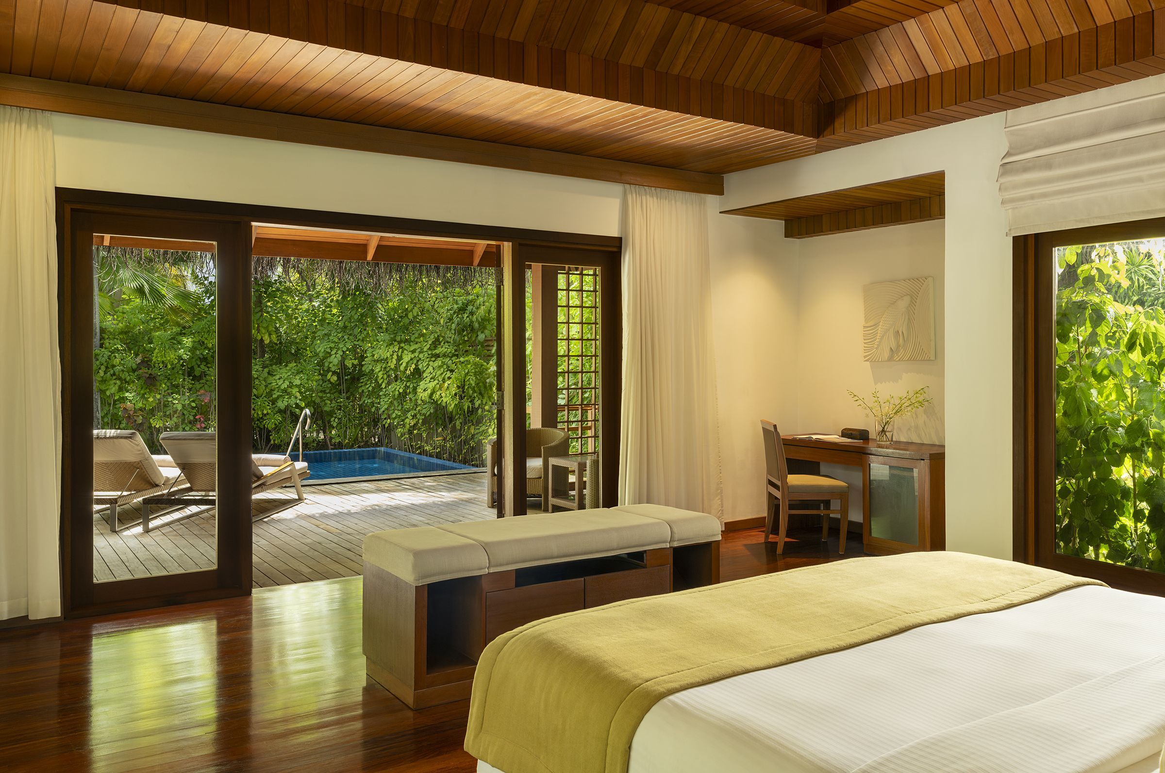 Bedroom of a Baros Pool Villa opening onto its deck and private pool