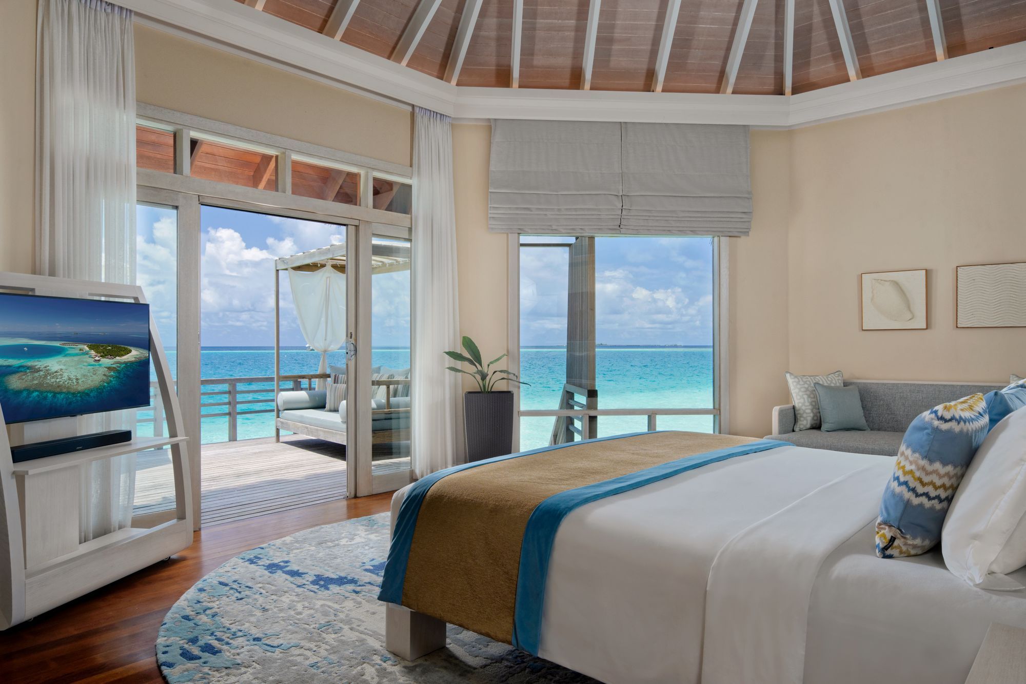 Bedroom of a Water Villa, with glass doors opening onto the lagoon