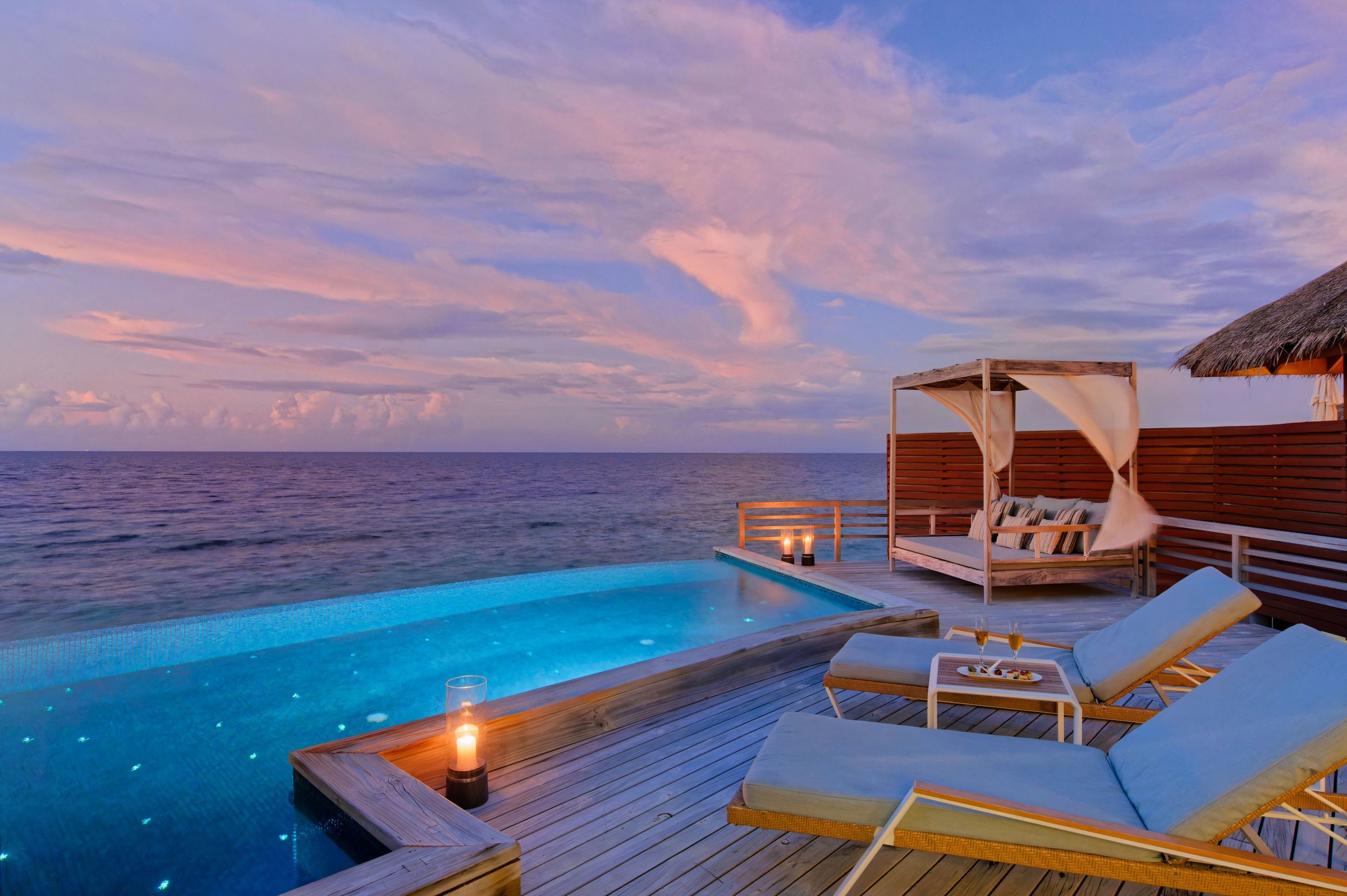 Sunset over the Indian Ocean from the infinity pool and deck of a Water Pool Villa
