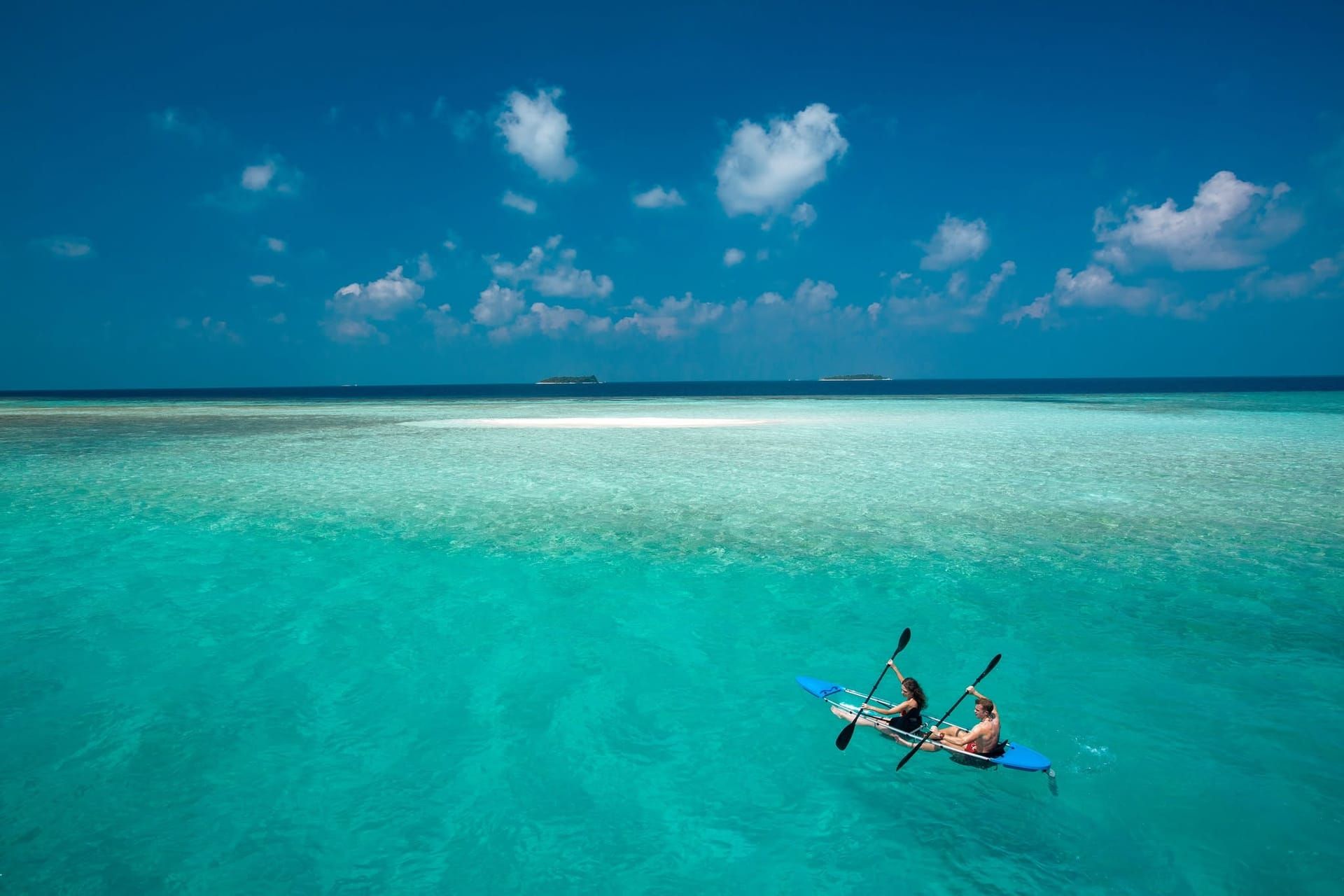 Two people paddling a kayak in a clear turquoise lagoon